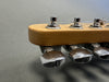 Close-up of guitar headstock tuning pegs with chrome machine heads and wrapped strings on light wood finish