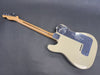 Rear view of cream Fender electric guitar with maple neck and chrome backplate on gray surface