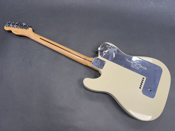 Rear view of cream Fender electric guitar with maple neck and chrome backplate on gray surface