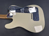 Fender electric guitar back view showing cream-colored body, chrome guitar neck plate, and chrome backplate with Fender logo and string ferrules on dark gray background.