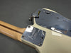 Close-up of Fender guitar neck plate with "Fender Corona California" engraving on cream body and maple neck with dark stripe on gray background
