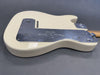 Cream Fender electric guitar body back with chrome control plate and wooden neck on gray background