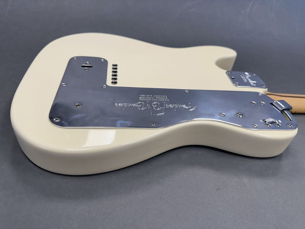 Cream Fender electric guitar body back with chrome control plate and wooden neck on gray background