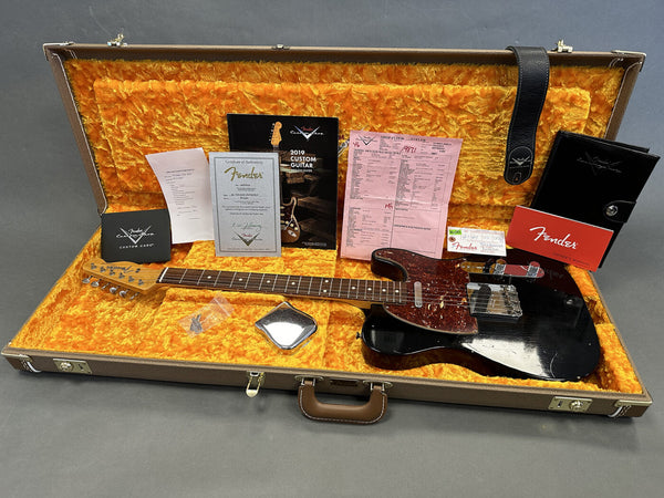 Fender Custom Shop black Telecaster electric guitar with tortoiseshell pickguard in open hard case with bright orange plush interior, including Fender certificate of authenticity, 2019 Custom Guitar Design Guide, shop spec sheet, owner's manual, guitar strap, and additional accessories.