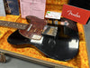 Vintage black Fender Telecaster electric guitar with tortoiseshell pickguard in a plush orange-lined hardshell case, including Fender owner's manual and documentation.
