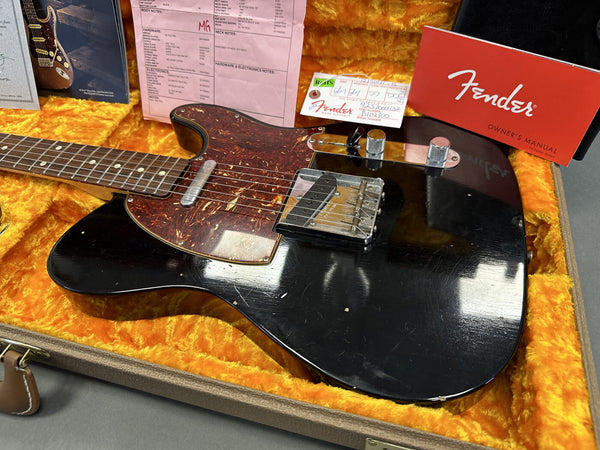 Vintage black Fender Telecaster electric guitar with tortoiseshell pickguard in a plush orange-lined hardshell case, including Fender owner's manual and documentation.