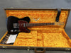 Black Fender Telecaster electric guitar with tortoiseshell pickguard inside open vintage-style hardshell case with bright orange plush interior and included Fender strap and documentation