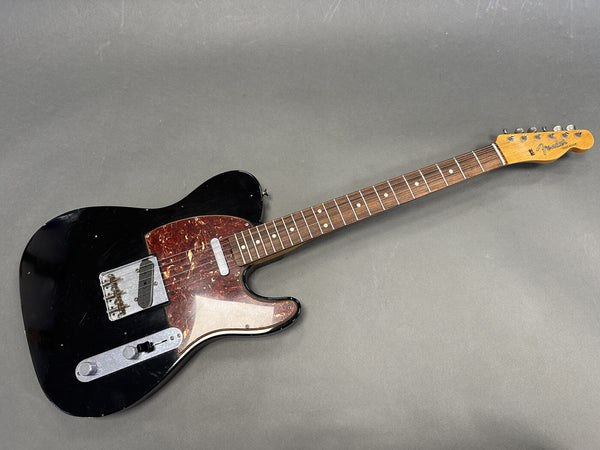 Fender Telecaster electric guitar with black body, tortoiseshell pickguard, rosewood fretboard, and maple neck on gray background