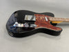 Black electric guitar with tortoiseshell pickguard, chrome hardware, and maple neck on gray background