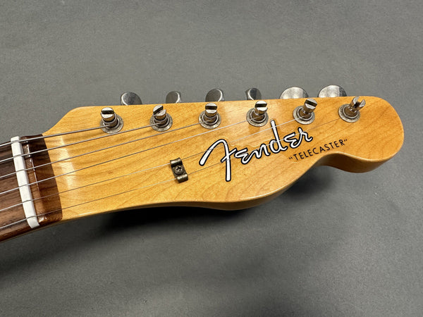 Close-up of Fender Telecaster guitar headstock with tuning pegs and strings on grey background
