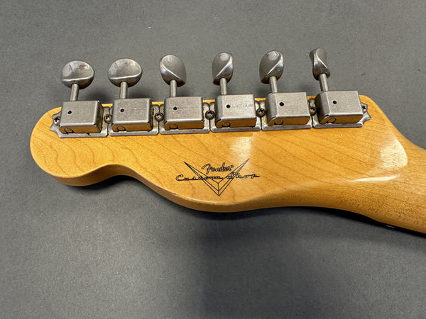 Back of Fender Custom Shop guitar maple headstock with vintage-style tuning pegs on gray surface