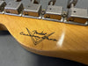 Close-up of Fender Custom Shop logo on natural wood guitar headstock with vintage metal tuning machines