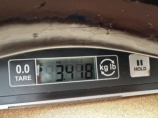 Digital scale display showing guitar weight of 3.418 kilograms on brown surface