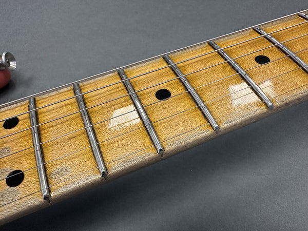 Close-up image of maple guitar neck with chrome frets and black dot inlays on guitar fretboard strings