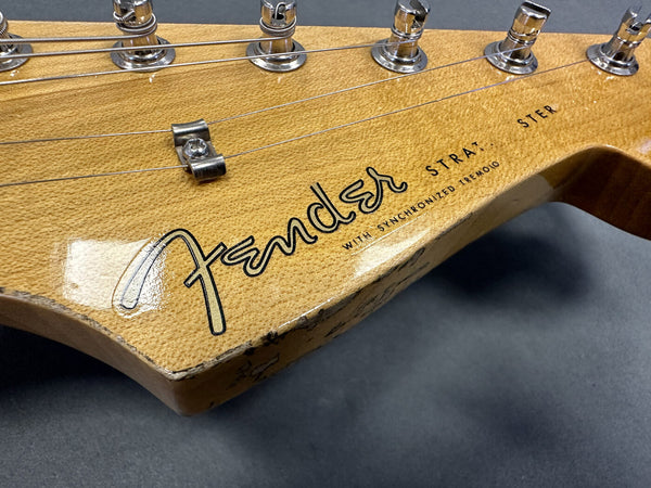 Close-up of vintage Fender Stratocaster guitar headstock with six tuning pegs and worn wood finish