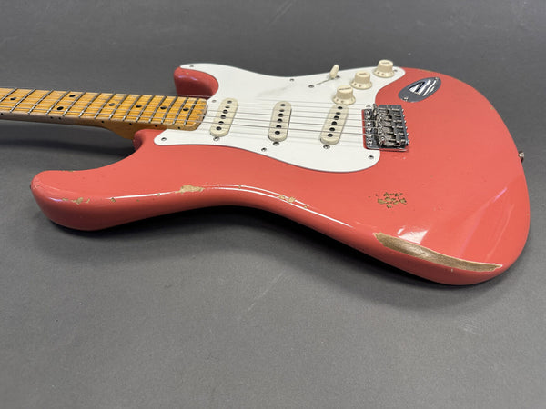 Used pink electric guitar with white pickguard and maple neck showing worn finish and vintage styling on gray background