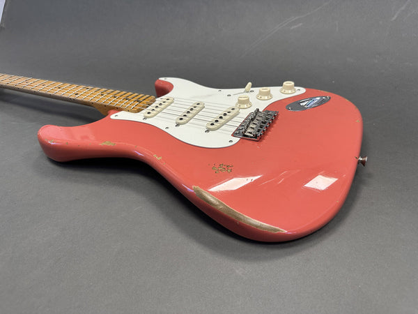 Vintage style worn coral red electric guitar with white pickguard and maple neck on gray background