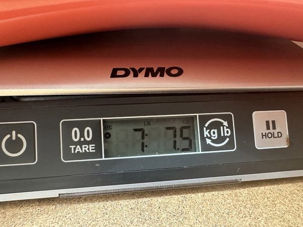DYMO digital scale displaying weight 7 pounds 7.5 ounces used for weighing guitars or musical instruments at Coffee House Guitars
