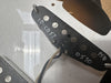 Close-up of black guitar pickup with visible magnets and white handwritten markings on white surface