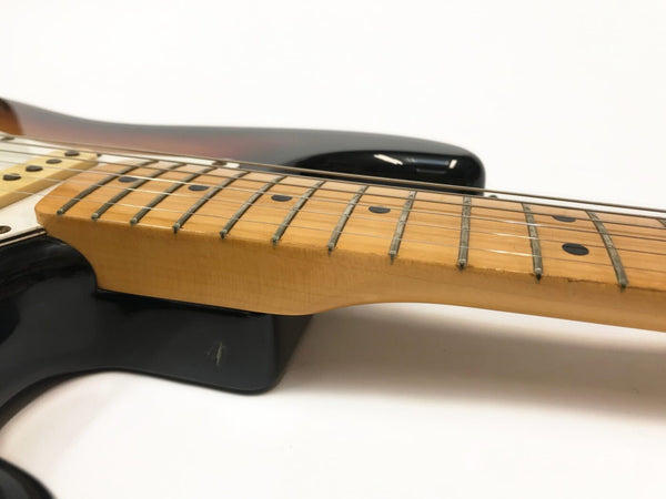 Close-up of electric guitar maple neck and fretboard with black dot inlays and six strings on black body background
