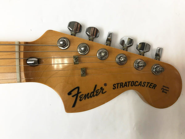 Fender Stratocaster guitar headstock with six chrome tuning pegs and strings attached, natural wood finish, original contour body text on headstock