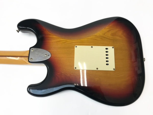 Back of sunburst Fender Stratocaster electric guitar showing wood grain and metal neck plate with Fender logo