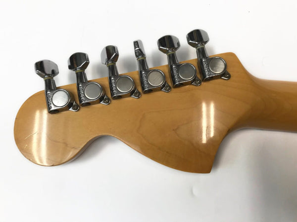 Close-up of maple guitar headstock with six vintage-style chrome tuning pegs on white background