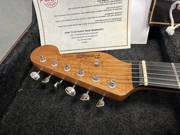 Close-up of Paoletti electric guitar headstock with tuning pegs and warranty card in guitar case interior