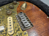 Close-up of rustic electric guitar bridge and pickups with brass pickguard and wooden body detailing