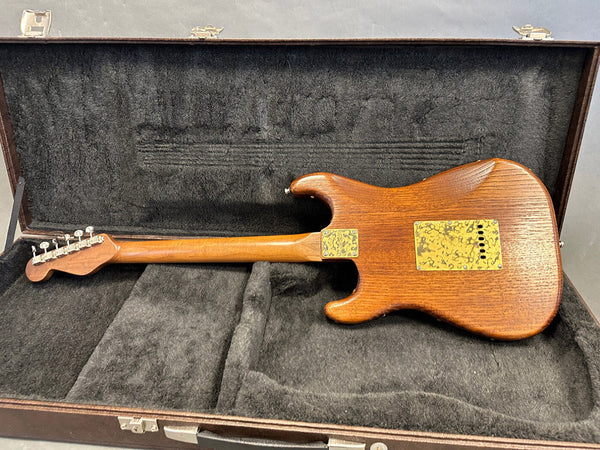 Back view of vintage electric guitar with natural wood finish and tortoiseshell pickguard plate inside black plush guitar case