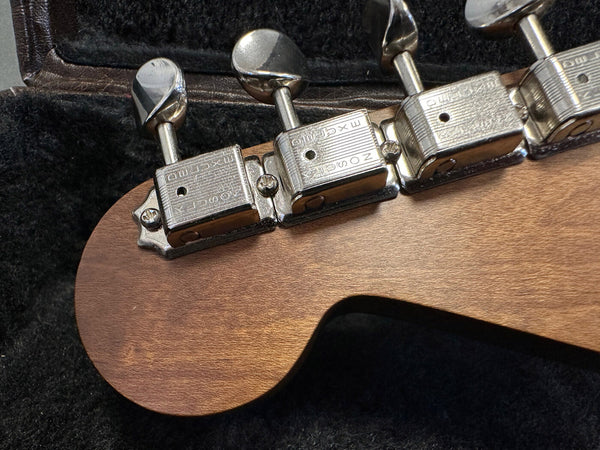 Close-up of vintage Zosick guitar tuning pegs on natural wood guitar headstock in black plush case