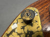 Close-up of Fiocchi 12 gauge shotgun shell casing used as a vintage guitar strap button on a wooden electric guitar with brass pickguard plating.