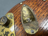Close-up of vintage brass output jack plate and control plate on a wooden electric guitar body with aged finish