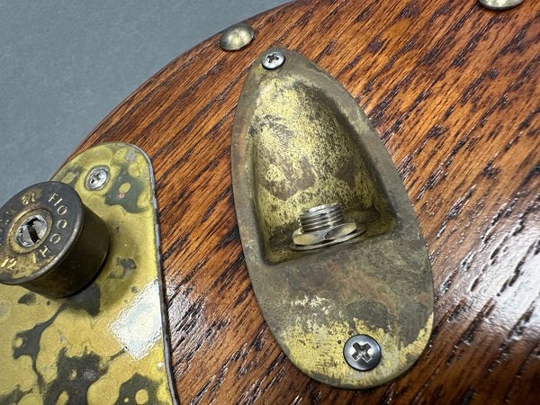 Close-up of vintage brass output jack plate and control plate on a wooden electric guitar body with aged finish