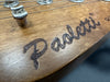 Close-up of a wooden guitar headstock with the engraved Darklotti logo and metal string guide at Coffee House Guitars