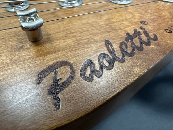 Close-up of a wooden guitar headstock with the engraved Darklotti logo and metal string guide at Coffee House Guitars