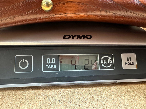 Close-up of digital scale showing guitar weight of 4.24 kilograms, DYMO brand scale with power, tare, unit conversion, and hold buttons.