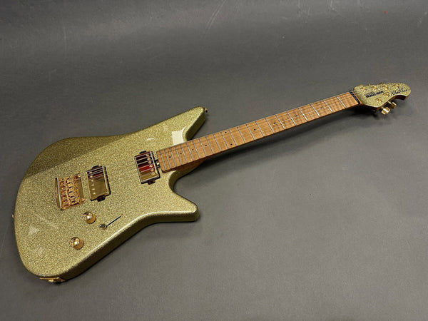 Electric guitar with gold sparkle finish, dual humbucker pickups, gold hardware, maple fretboard, and unique offset body design on gray background
