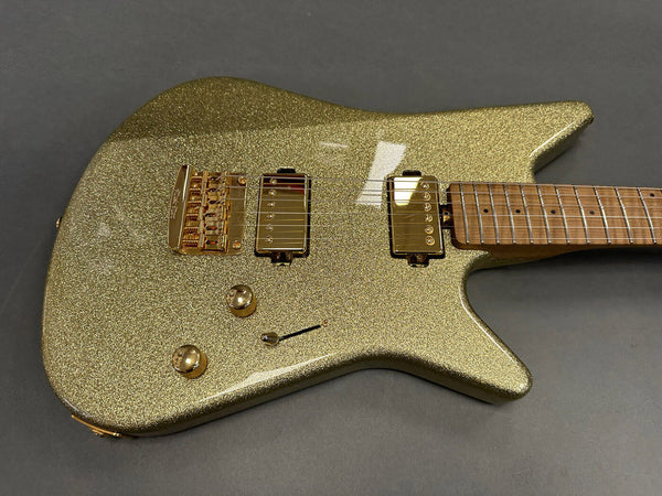 Electric guitar with gold sparkle finish, gold hardware, dual humbucker pickups, maple neck, and two control knobs on dark gray background