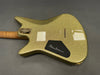 Back view of gold sparkle finish electric guitar body with signature on the black plate, showing string ferrules and wood neck with gold neckplate
