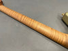 Close-up of flamed maple guitar neck with gold tuning peg on gray background