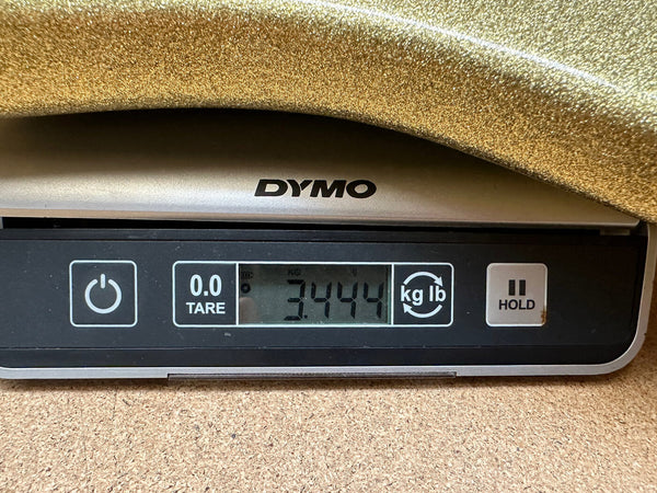 Digital scale weighing a metallic gold guitar body showing 3.444 pounds on DYMO scale display
