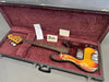 Vintage Fender Precision Bass guitar with sunburst finish and tortoiseshell pickguard in black hard case with red plush interior, includes Fender owner's manual and additional papers