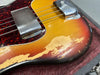 Close-up of vintage sunburst electric guitar body with worn and chipped finish, tortoiseshell pickguard, and metal pickup covers resting in a padded guitar case