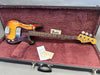 Vintage Fender Precision Bass guitar with sunburst finish and tortoiseshell pickguard in open black hard case with plush red interior, including Fender owner's manual and two documents