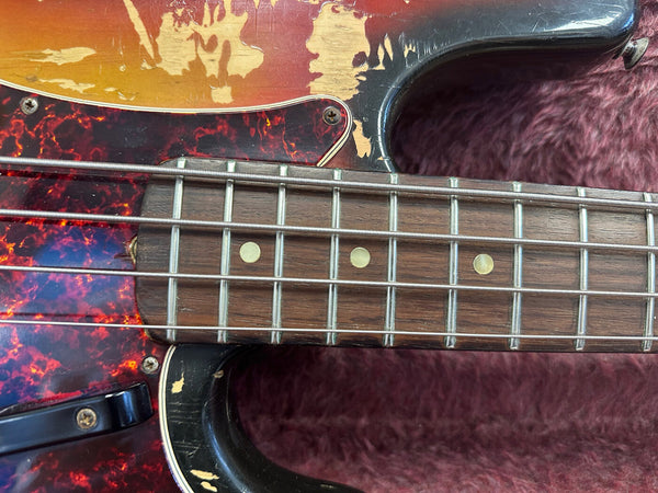 Close-up of vintage electric bass guitar fretboard with rosewood fingerboard and worn sunburst finish on body with tortoiseshell pickguard