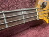 Close-up of a Fender bass guitar maple neck with rosewood fretboard and metal frets on a purple plush background