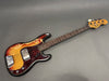 Vintage Fender Precision Bass with sunburst finish and tortoiseshell pickguard, showing wear and aging on body and hardware, with rosewood fingerboard and four tuning pegs on the natural wood headstock.