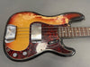 Vintage sunburst electric bass guitar with worn finish and tortoiseshell pickguard, showing metal pickup covers and control knobs, photographed on gray background