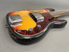 Vintage sunburst electric bass guitar with tortoiseshell pickguard and chrome hardware, worn finish, close-up angle on body and controls